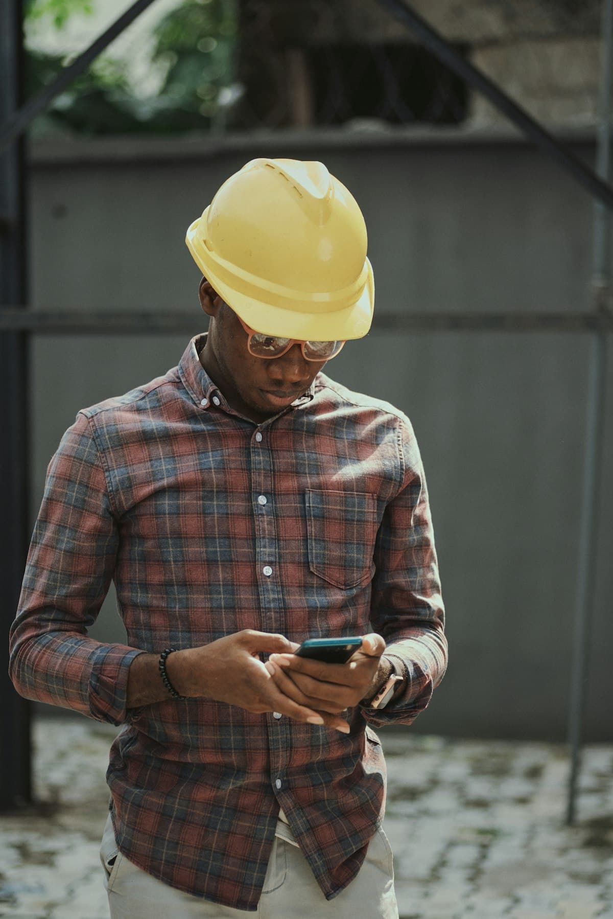 Un artisan casqué consulte son téléphone sur un chantier