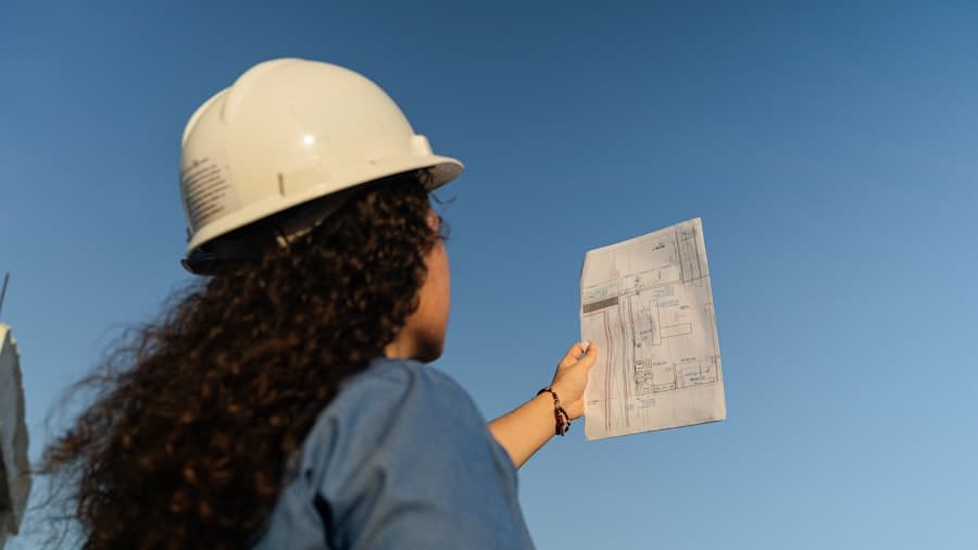 Une conductrice de travaux consulte un plan sur un chantier
